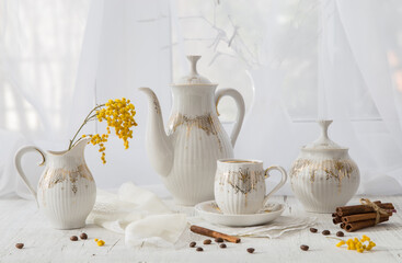 Modern still life with a coffee set and a spring mimosa branch on a light windowsill