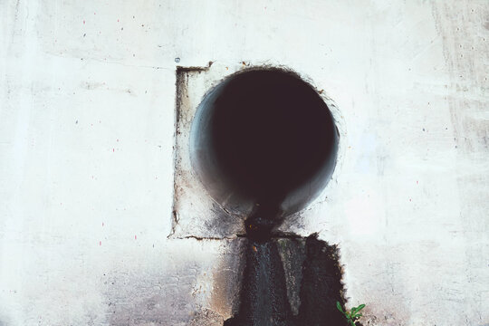 Dirty water flows out of the old rusty pipe without cleaning. Pollution of natural water bodies. Kingfisher bird in corner