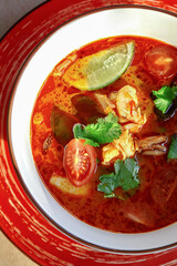Rich Thai Tom Yum soup with shrimp, squid, mushrooms, tomatoes, and lime