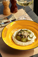 Beef stroganoff with mashed potatoes and pickles on yellow plate
