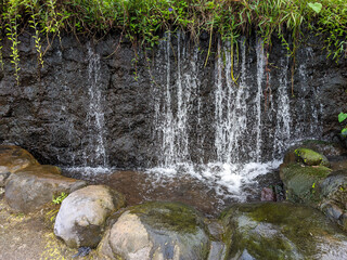 Nestled in a lush enclave, a waterfall cascades gently, its waters whispering tales of serenity.