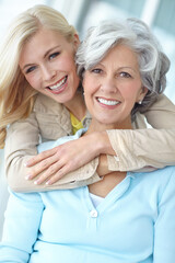 Portrait, happy and mother with daughter in house for love, bonding and together in living room. Senior woman, girl and hug with smile in home for connection, care and family time while on retirement