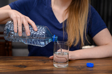 Kobieta nalewa czystą wodę do picia do szklanki 