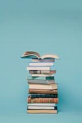 Education concept: Side view of stack of books with open book on top. Light blue background.