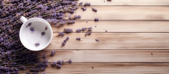 Top view of a white porcelain cup filled with dried lavender flowers scattered on a wooden surface...