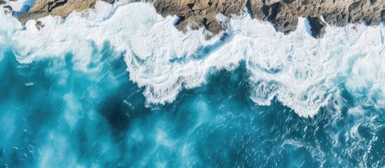 Bird s eye view of crashing blue waves on a rocky Australian coastline with a summer seascape Ideal travel concept background with a beautiful copy space image available - Powered by Adobe