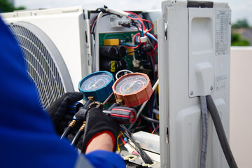 Air conditioner service .The air conditioner technician is using a gauge to measure the refrigerant pressure. air compressor.