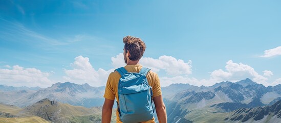 Copy space image of a young man with a backpack in the mountains against a blue backdrop enjoying his summer vacation and adventure captured in a lifestyle moment from a close up rear view - Powered by Adobe