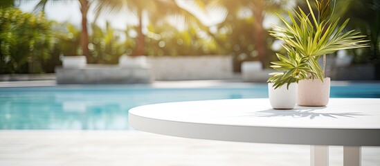 A white marble table with ample copy space image overlooking a blurred sunny pool in a tropical resort perfect for showcasing or editing your products