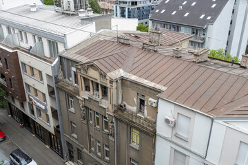 An aerial view of a cityscape juxtaposing a historical building with broken windows and a brown...