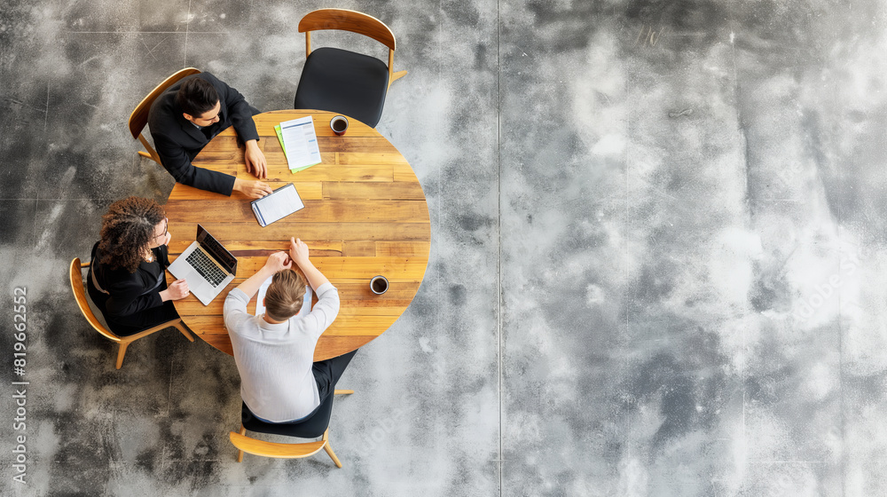 Poster a top-down view of three professionals working at a round wooden table, concrete-style background, b