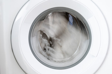 Close-up laundry running washing machine at home, amid a washing cycle, home electronics concept