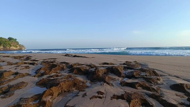Landscape view of sea sand and coral rocks on a sunny summer day in the afternoon. Molang Beach, Tulungagung, Indonesia