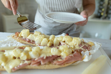 Woman preparing delicious baked sandwich with asparagus, ham and cheese in the kitchen