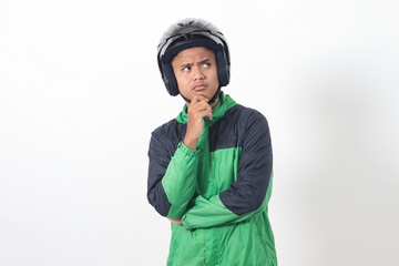 Portrait of Asian online taxi driver wearing green jacket and helmet thinking about question with hand on chin. Isolated image on white background