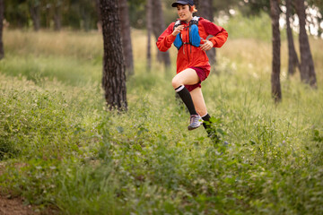 A woman in a red jacket and black socks runs through a forest. Concept of freedom and adventure as the woman enjoys her run in the natural setting