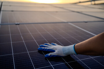 A person wearing a blue and white glove is touching a solar panel. Concept of caution and care, as...