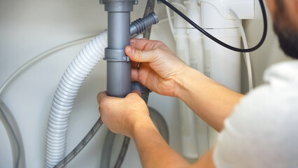 Close up of plumbers hands repairs plumbing pipes. Removing blockage clog in drain pipe. Installing...