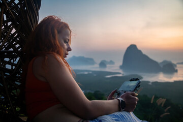 A beautiful girl looks at the dawn. Girl with red hair. Colorful dawn.