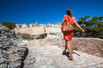 Young female tourist admiring the Old Town of Bonifacio, the limestone cliff, South Coast of Corsica Island, France