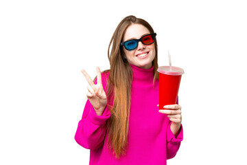 Young woman holding soda while watching a 3D movie smiling and showing victory sign