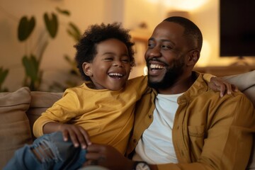 A father and son sitting on a couch laughing together while watching a comedy show on television in their living room