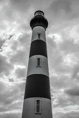 Lighthouse in the Outer Banks of North Carolina with a small building in front of it on a cloudy day