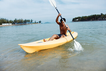 Active Asian Man Enjoying Kayaking Adventure on Tropical Beach