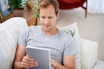 Man, tablet and reading online in living room for social media, movies and communication on sofa....