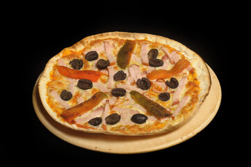 Pizza with ham, tomato and olives on a black background