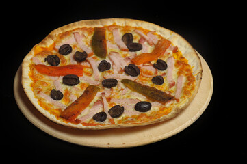 Pizza with ham, tomato and olives on a black background