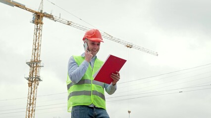 Cheerful foreman talking on cellphone on development site