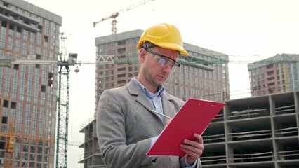 Construction inspector making notes during inspection of building objects
