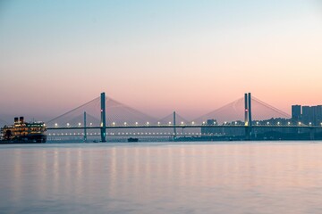 Majestic vessel illuminated under a grand bridge in a tranquil evening setting in Wuhan, China