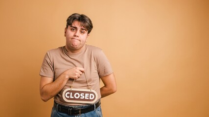 Sad man showing closed sign and gesturing in beige studio
