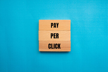 Pay per click words written on wooden blocks with blue background. Conceptual pay per click PPC...