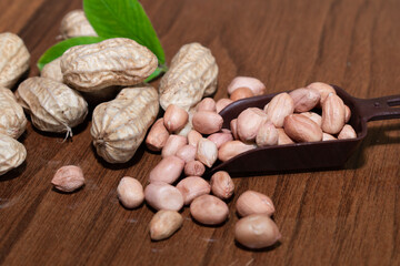 Fresh peanuts and leaves in bowl on wooden table