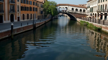 Obraz premium The serene waters of a canal flow underneath a historic arched bridge in a picturesque European town