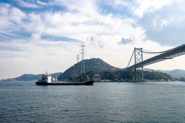 関門海峡に架かる関門橋の下を通過する貨物船