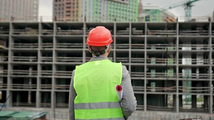 Construction superintendent with drawings approaching new building