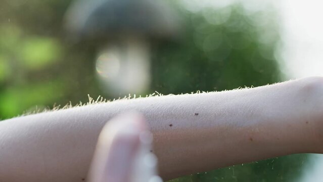 Slow motion of a person spraying arm with a tick prevention spray. Using an anti tick spray during the summer time to decrease the risk of tick bites. 