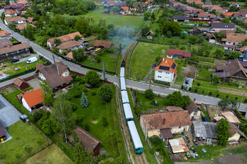 Fototapeta premium Aerial view of the old narrow-gauge Sovata train passing through a rural area