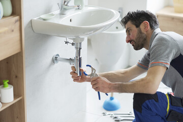 Professional plumber checking a sink drain