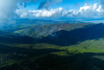 Cloud shadows on the Carpathian mountains seen from above. Aerial landscape with mountains and green forests