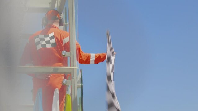 Man holding and waving Checkered race at finish line on a raceway. Victory, achievement, success and sport concept. Grand Prix.