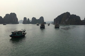 A group of boats are floating in the water near a mountain in Ha Long Bay Hanoi Vietnam