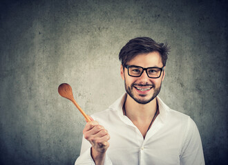 Happy handsome man with wooden spoon smiling at camera 