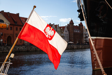 Polish flag with national coat of arms used as a naval ensign of Poland. Port in the Gdansk city, Baltic sea travel destination