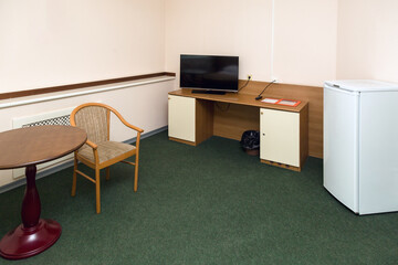 Spacious hotel room with furniture and green carpet floor.