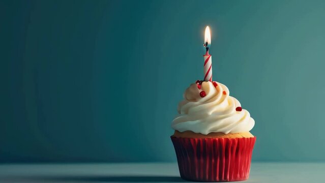 A red cupcake with a lit candle on top